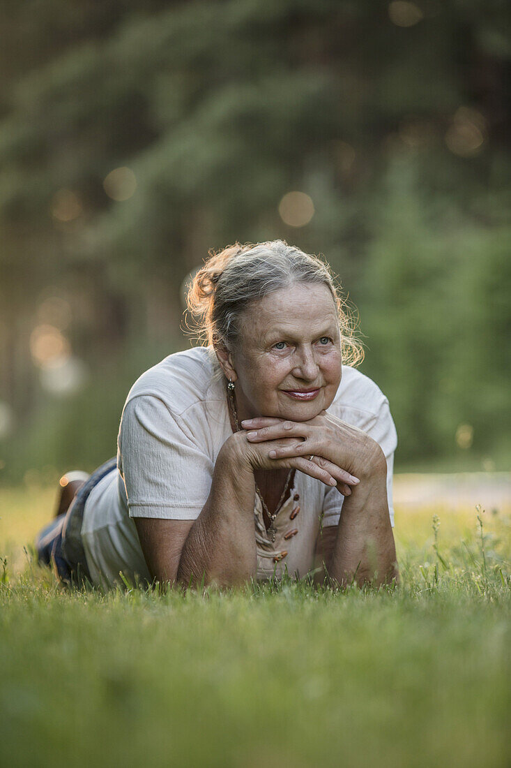 Thoughtful senior woman lying in park
