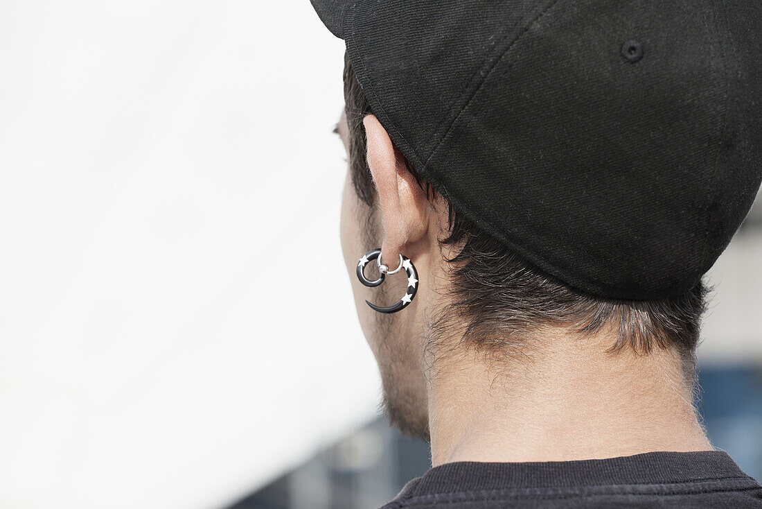 Rear view of young man wearing stud earrings outdoors