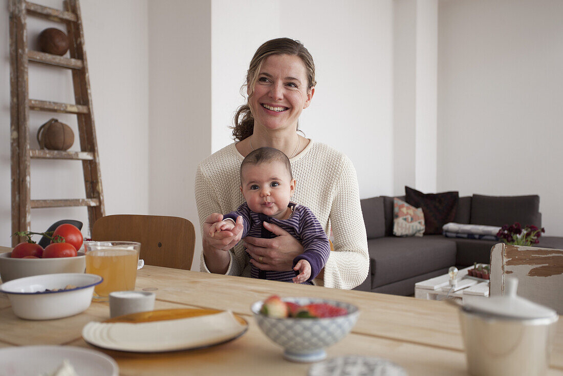 Smiling mother sitting with baby girl at table