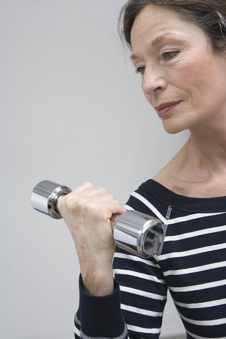 Mature woman holding hand weight