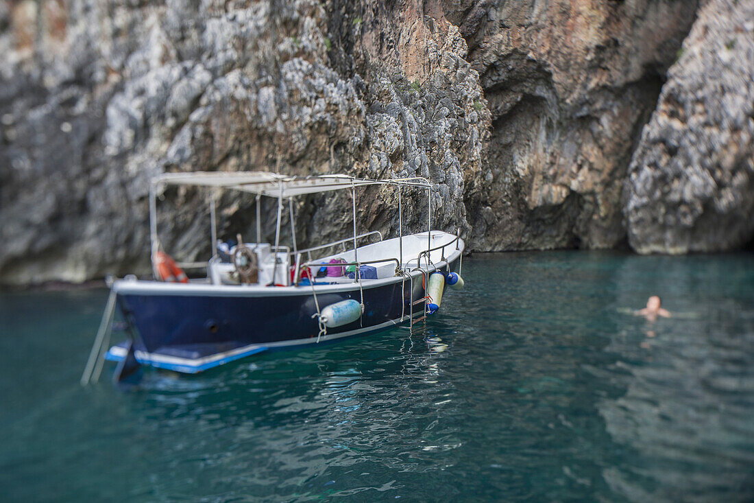 Boat floating on water by rock formation