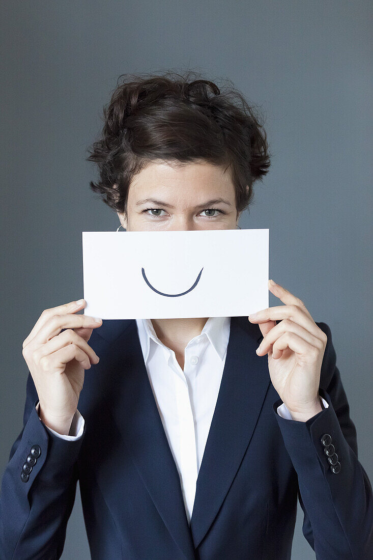 Portrait of mid adult woman holding paper with curve sign, close-up