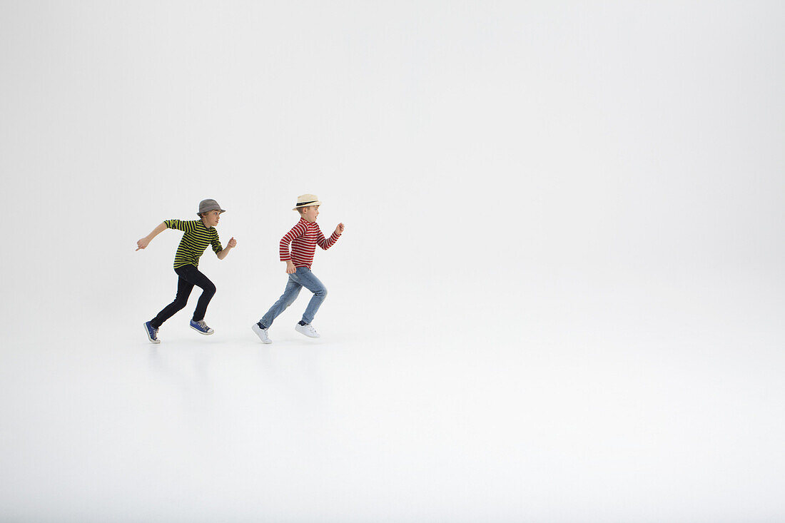 Two boys running against white background