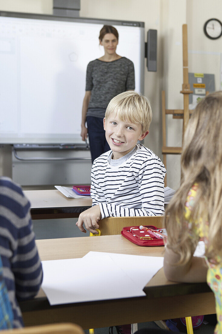 Boy sitting in classroom, smiling