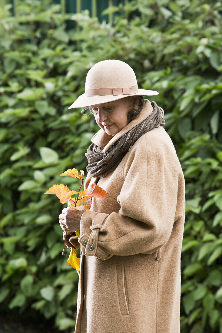 Senior woman looking at autumn leaves