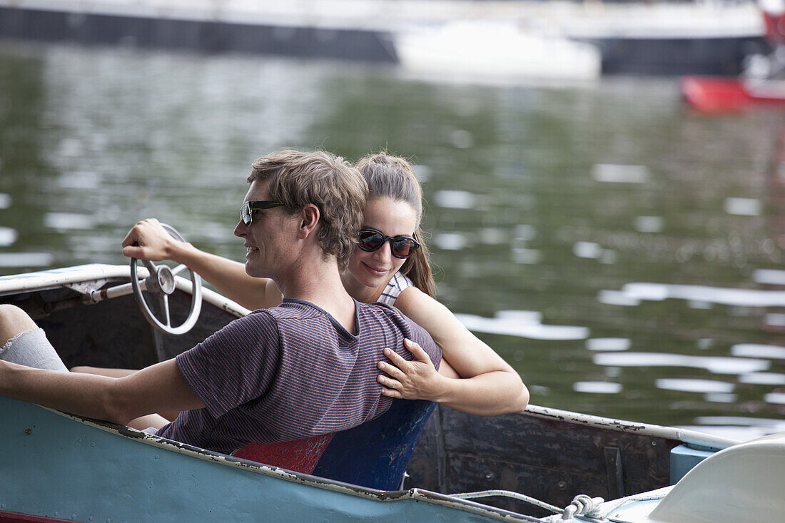 Young couple riding paddle boat on lake