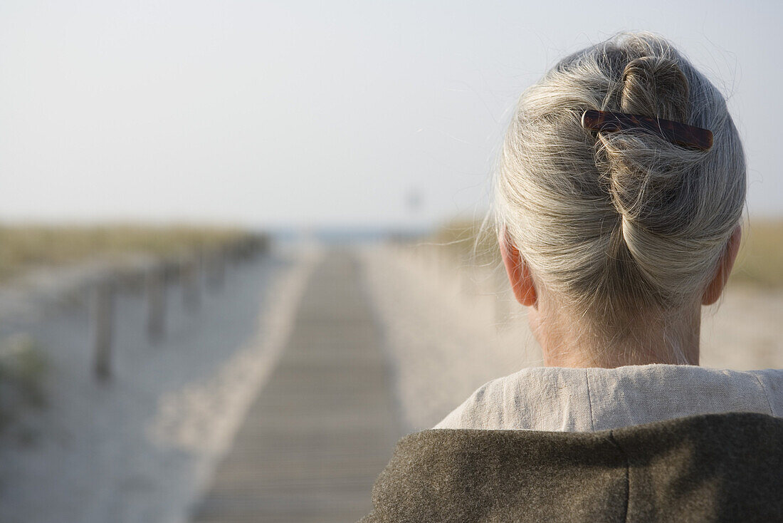 Mature woman standing on boardwalk at beach