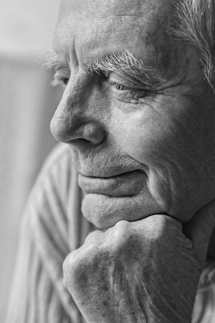 Thoughtful senior man with hand on chin looking away