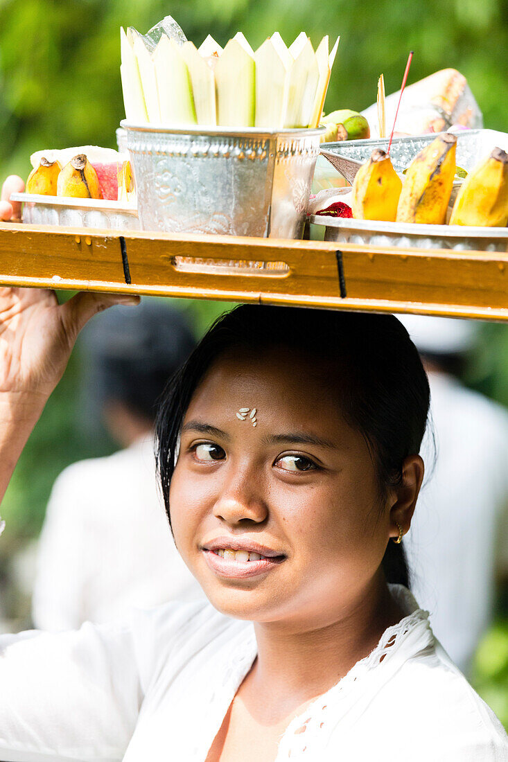 Junge Frau trägt Tablett mit Opfergaben auf dem Kopf, Odalan Tempelfest, Munduk, Bali, Indonesien
