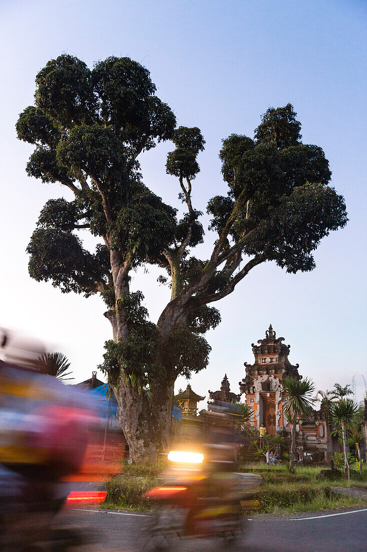 Mopeds passing, temple gate in background, Sidemen, Bali, Indonesia