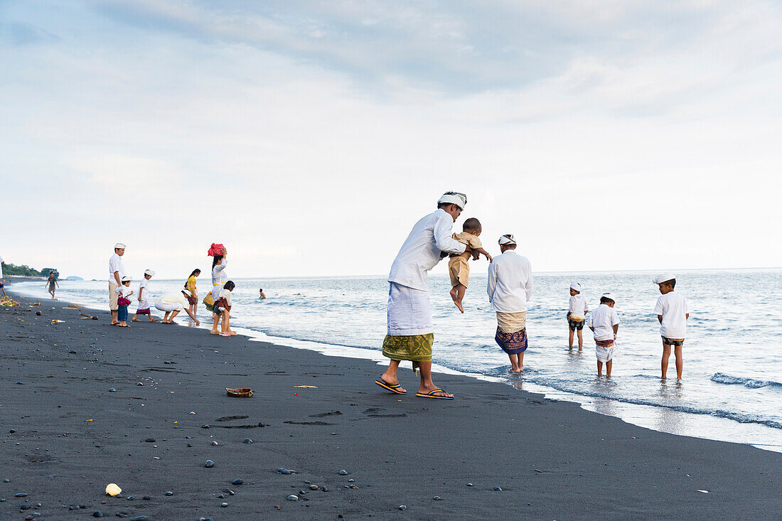 Familien am Strand nach Odalanfest, Tempel Pura Goa Lawah, Padang Bai, Bali, Indonesien