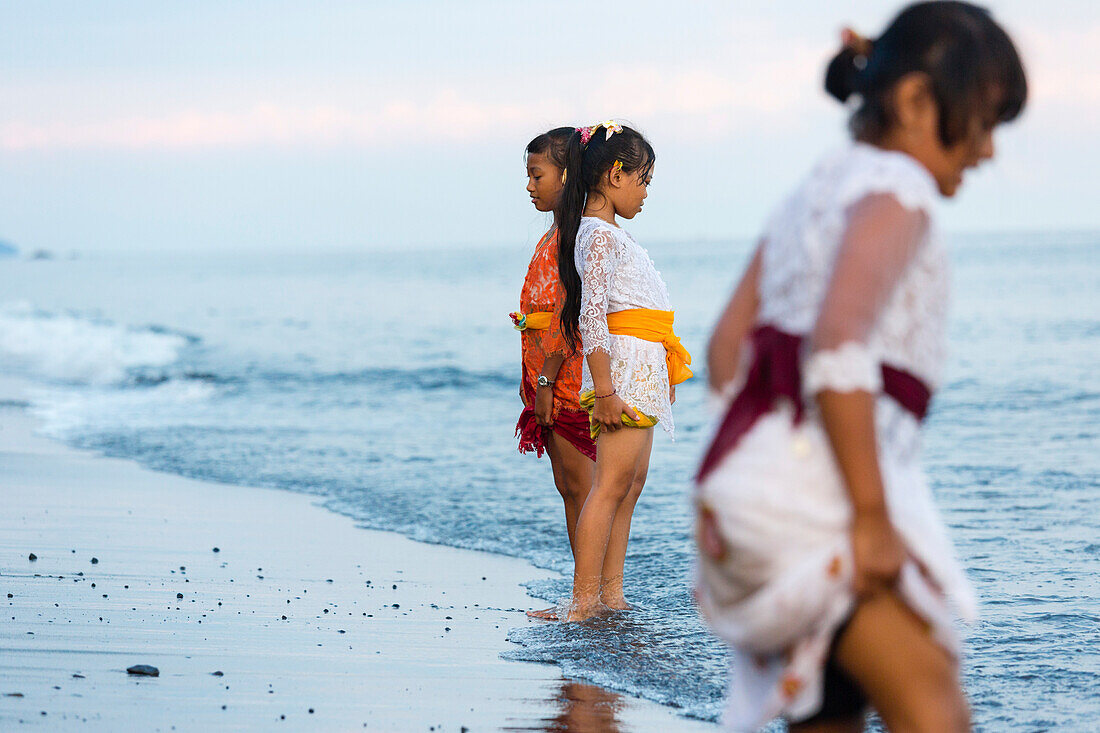 Girls standing in shallow water, Odalan, Pura Goa Lawah, Padangbai, Bali, Indonesia