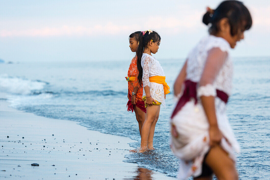 Mädchen stehen im seichten Wasser, Odalanfest im Tempel Pura Goa Lawah, Padang Bai, Bali, Indonesien