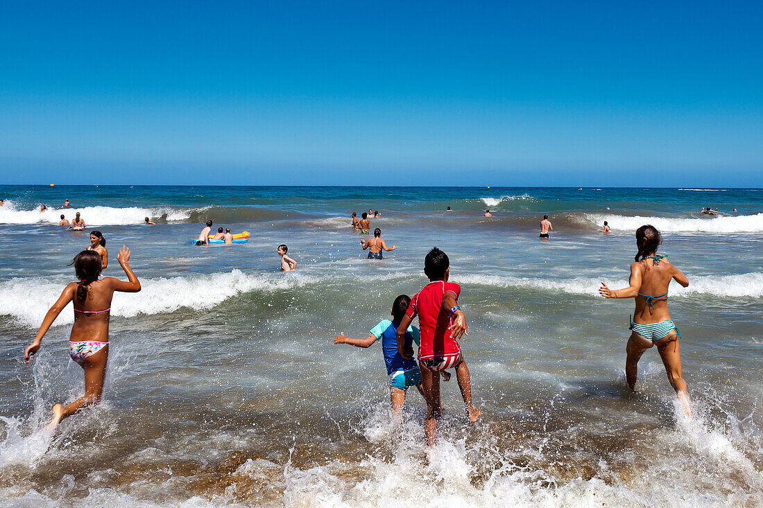 Children running into the sea, Playa del Ingles, Gran Canaria, Canary Islands, Spain