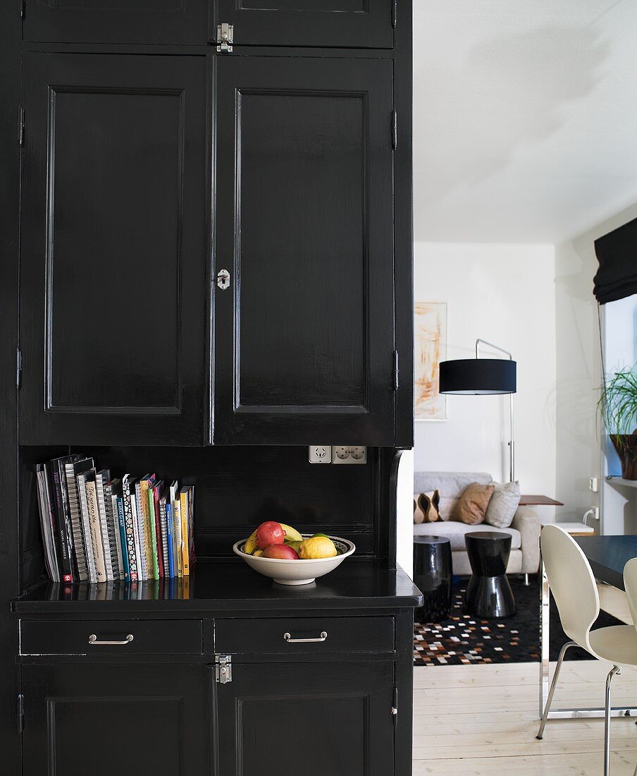 Schwarzer Küchenschrank und Blick in offenes Wohnzimmer