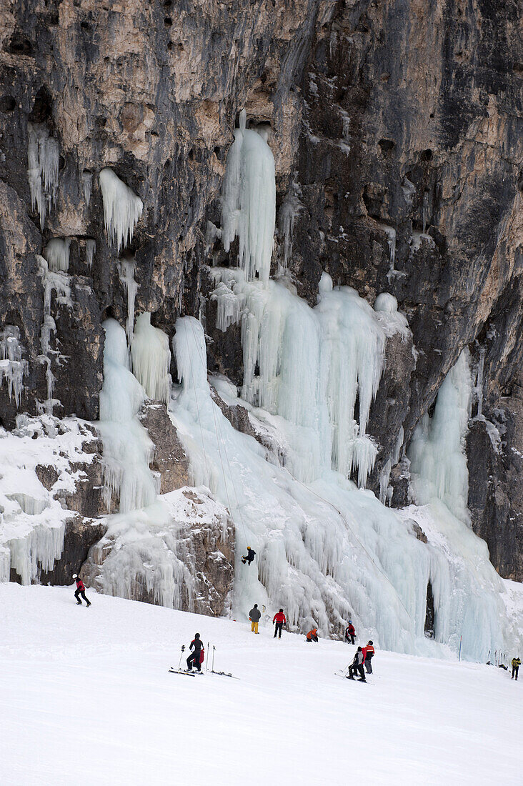 Skiers observe ice climber on rock face at Lagazuoi, South Tyrol, Italy
