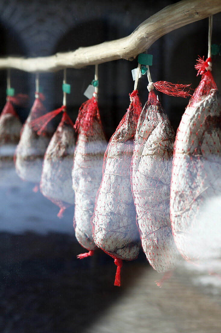 Detail of prosciutto hanging in a shop window