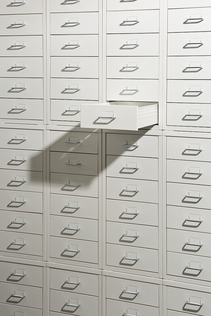 A white cabinet of drawers with one drawer open