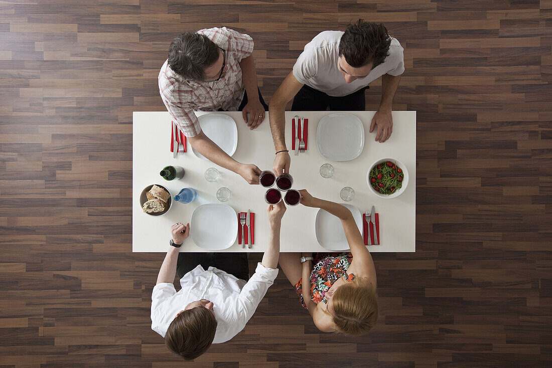 Four friends toasting at a dinner party, overhead view