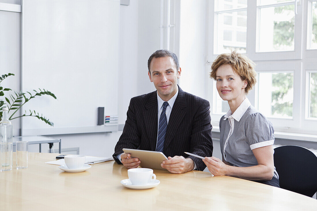A businessman and businesswoman using a digital tablet in a meeting