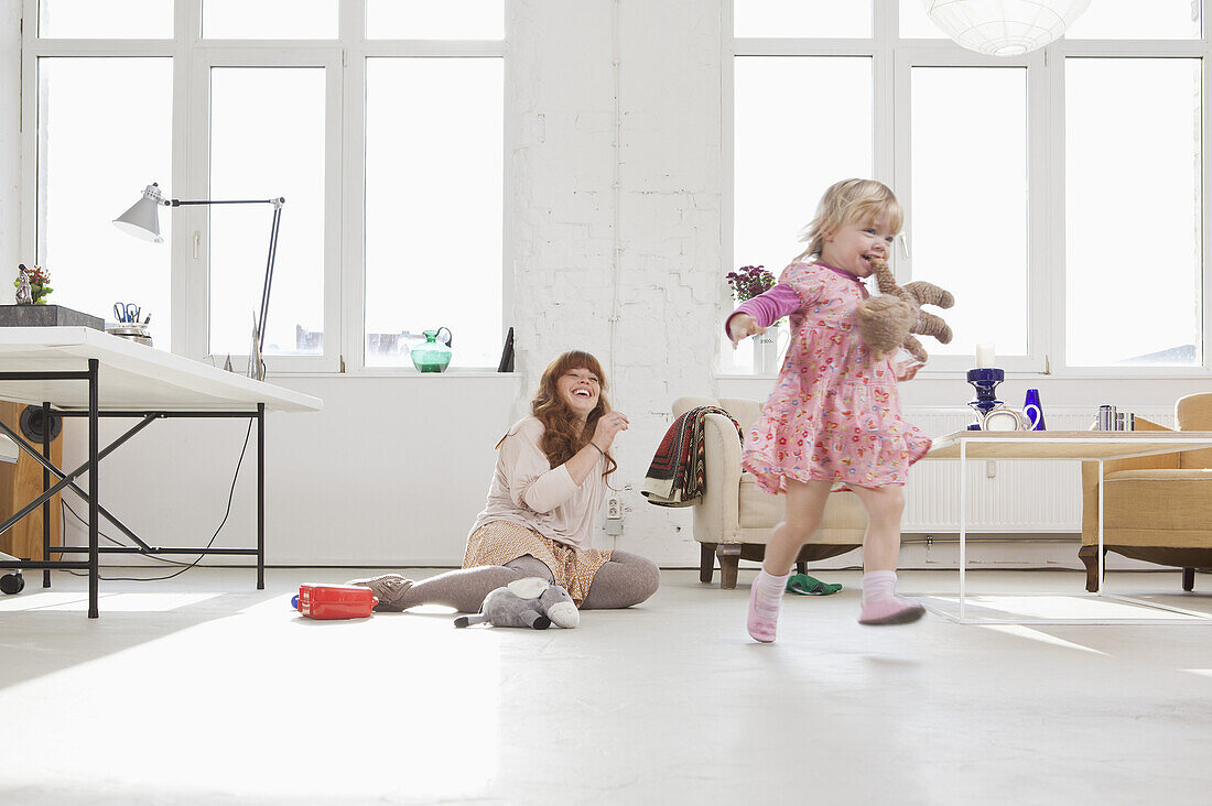 A young girl carrying a stuffed toy in her mouth running around