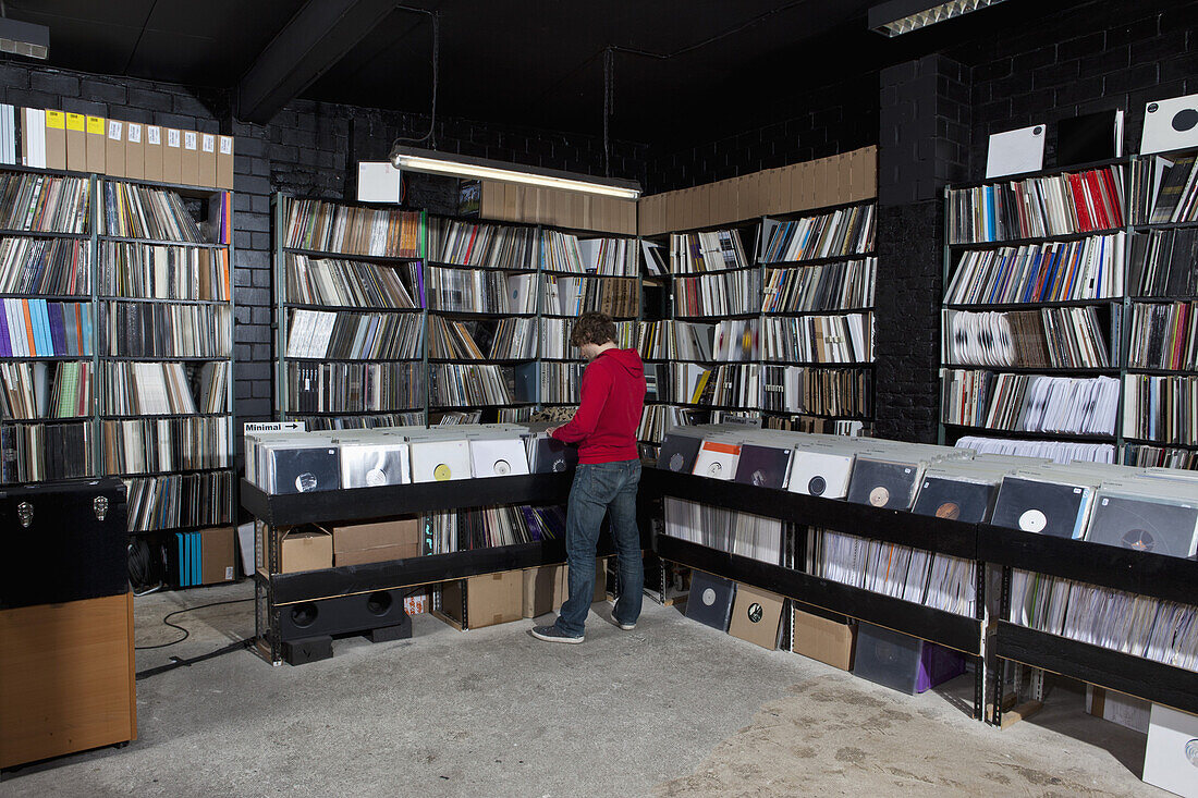 A young man searching through records, rear view