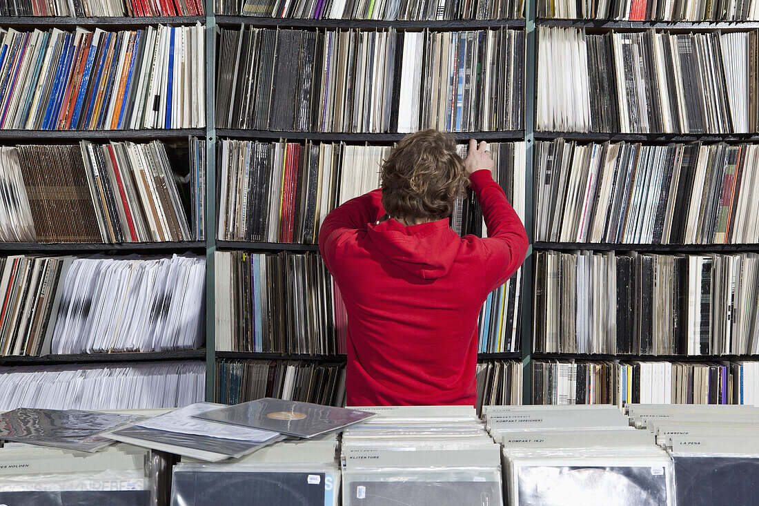 A young man selecting a record from a shelf in a record store