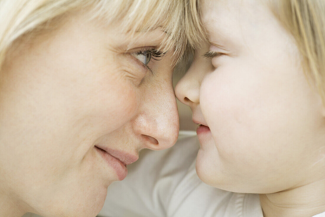 A mother and daughter lying down, face to face, close-up