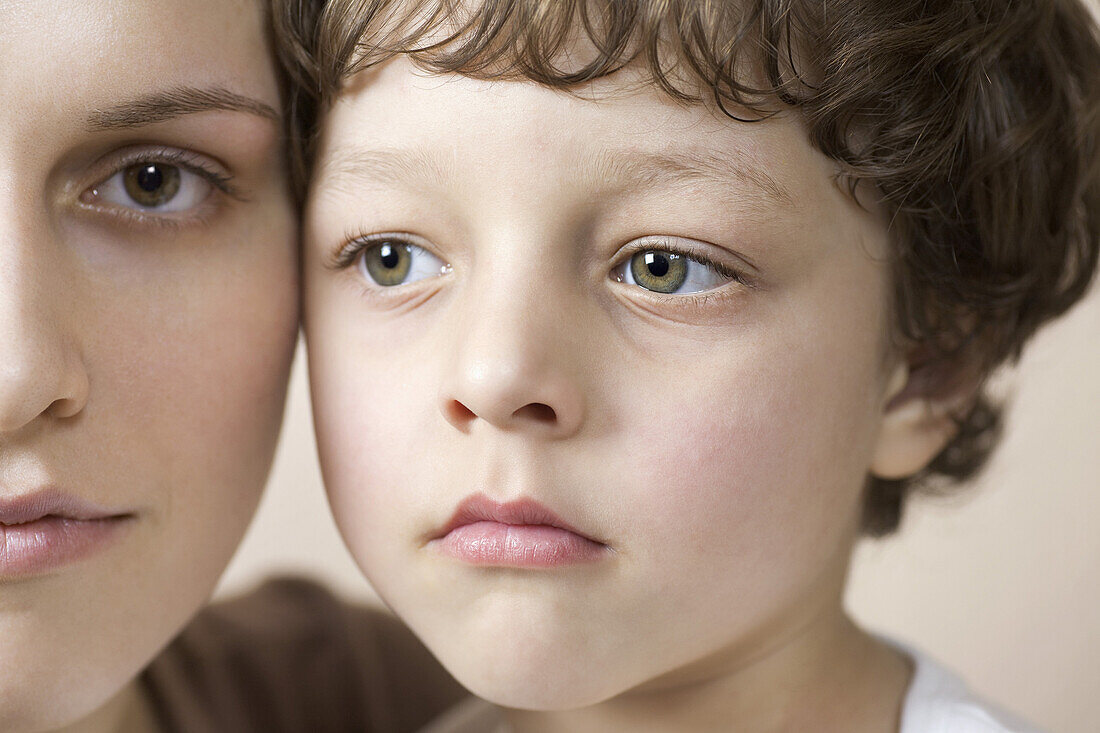 A young boy and his mother cheek to cheek