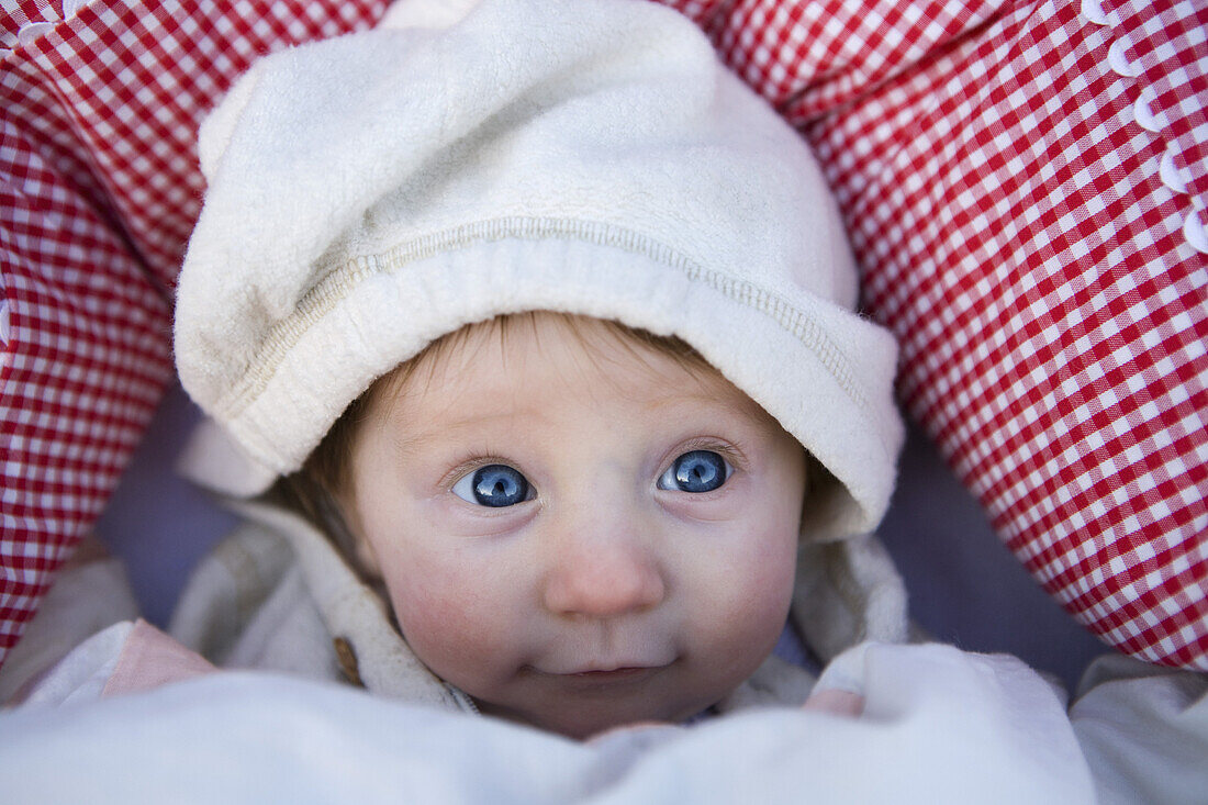 A baby wearing a hooded shirt, looking up
