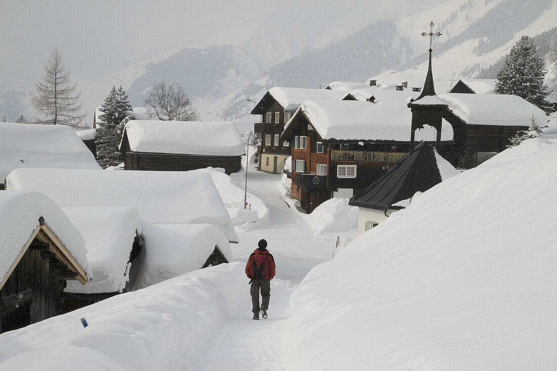 Man strolling through snow covered village