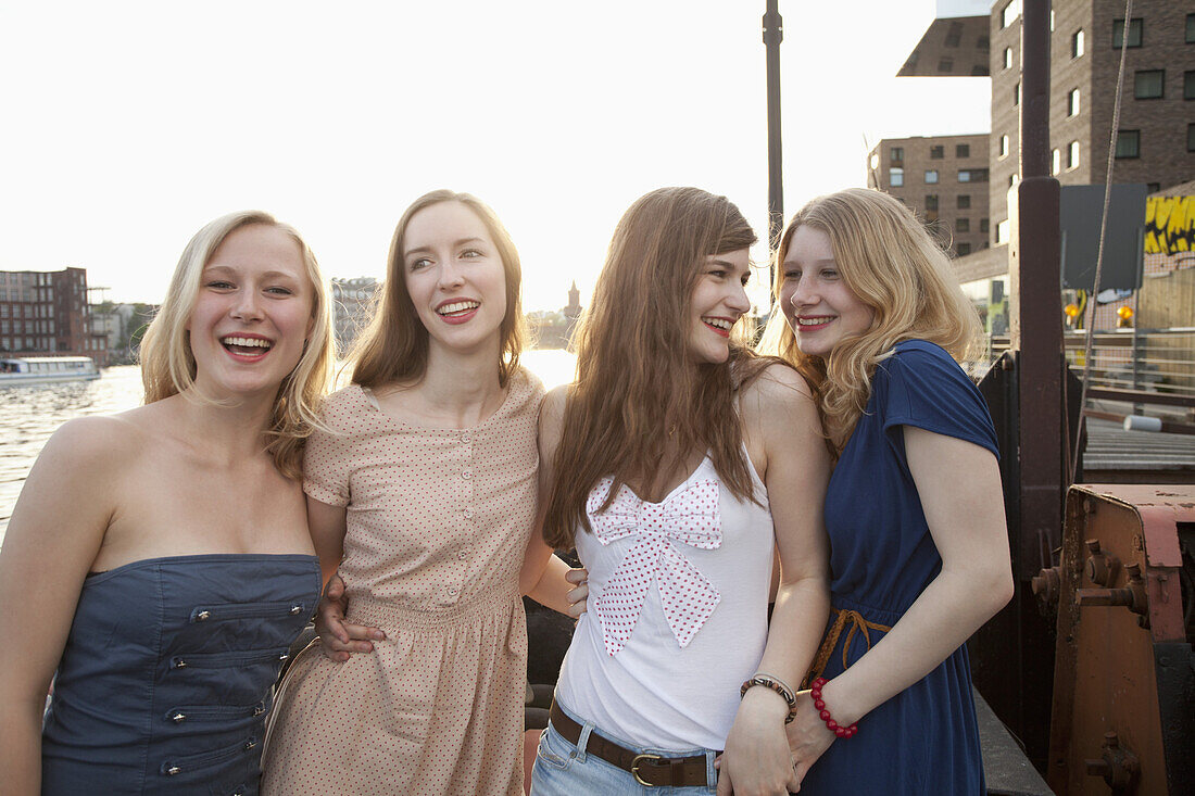 Four female friends standing side by side, Spree River, Berlin, Germany