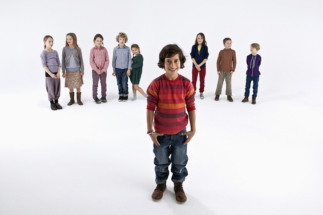 A boy standing in front of a line of kids