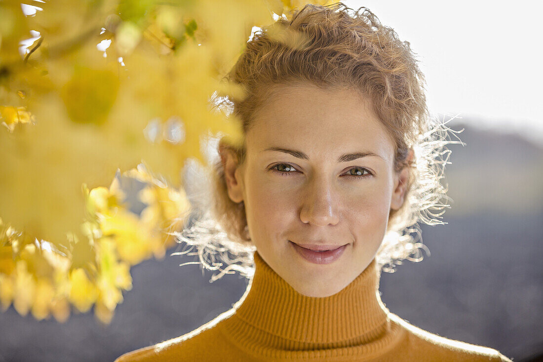 A beautiful woman standing near a tree in autumn