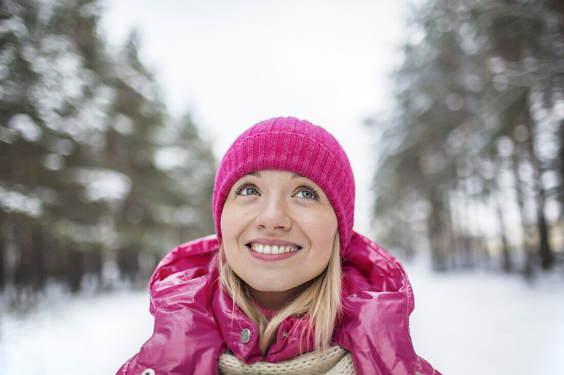 A beautiful woman in a knit cap looking up, outdoors in winter