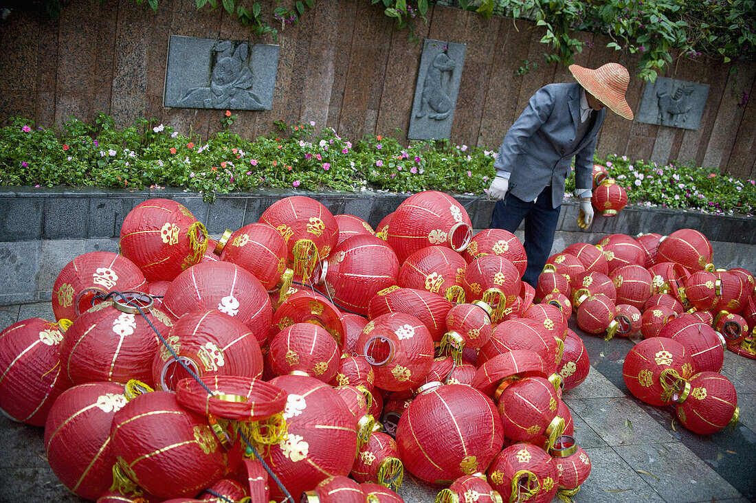 A worker considering a pile of Chinese lanterns