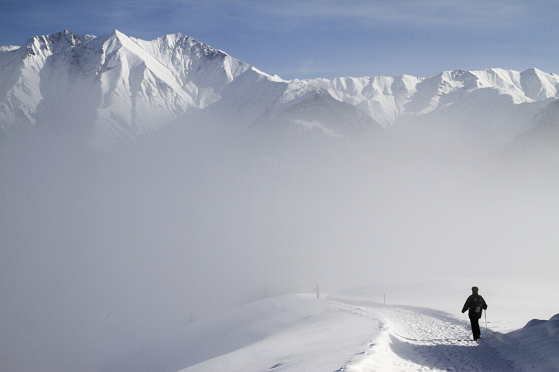 Hiking on trail by snowy mountain range