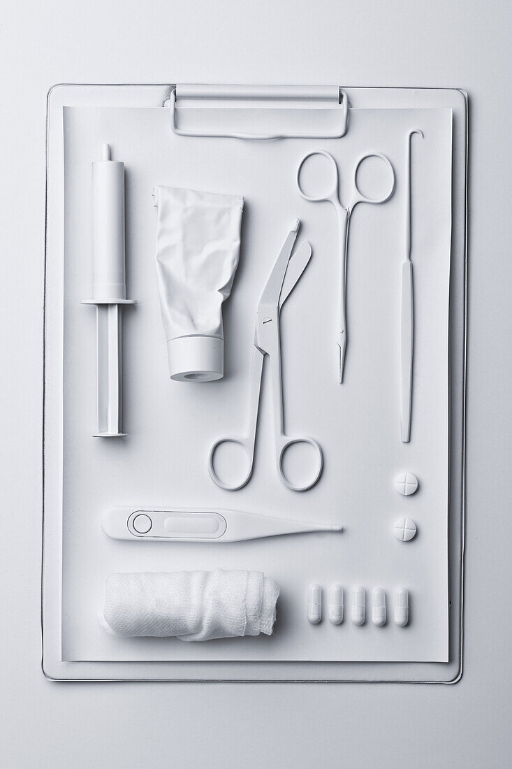 Medicine and medical equipment painted white and laid out on a clipboard