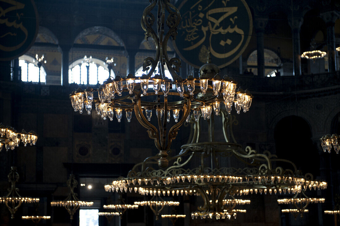 Chandeliers hanging in the Blue Mosque, gold Arabic script in background, Istanbul, Turkey