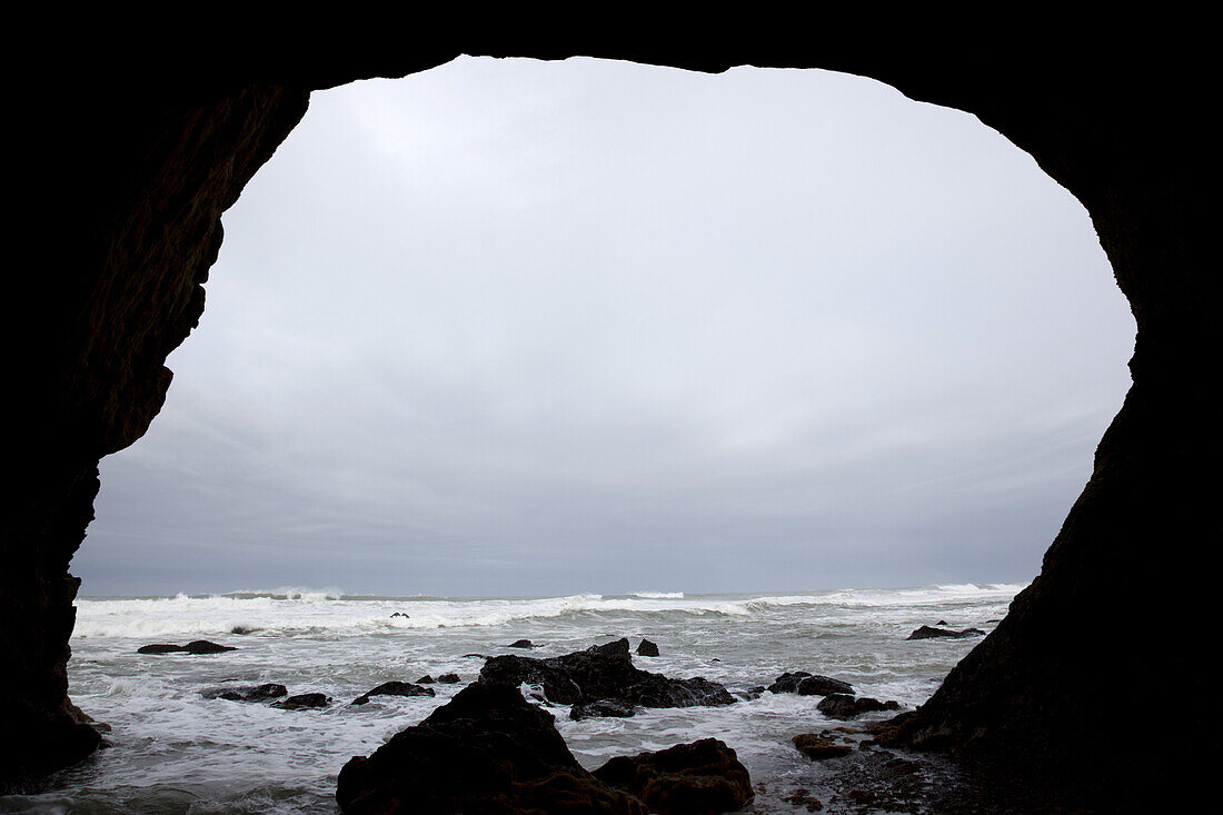 A cloudy overcast sky over the ocean seen from a darkened cave