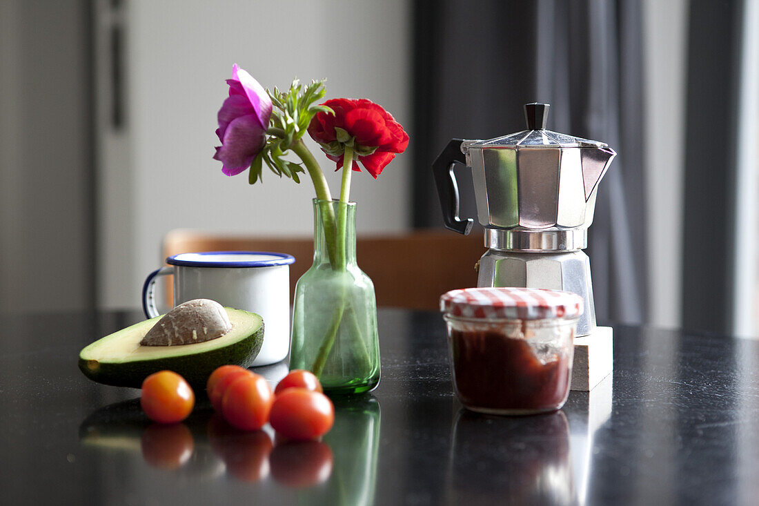 A table with espresso maker, coffee cup and ingredients for breakfast