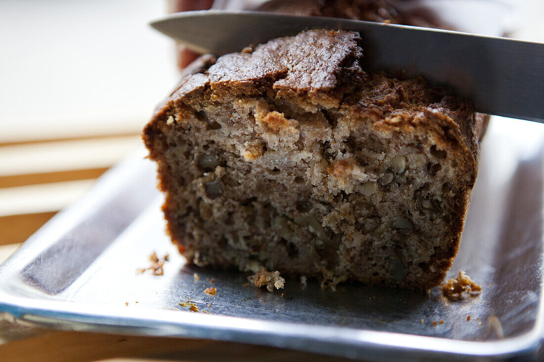 A knife cutting into a loaf of banana bread in a cafe