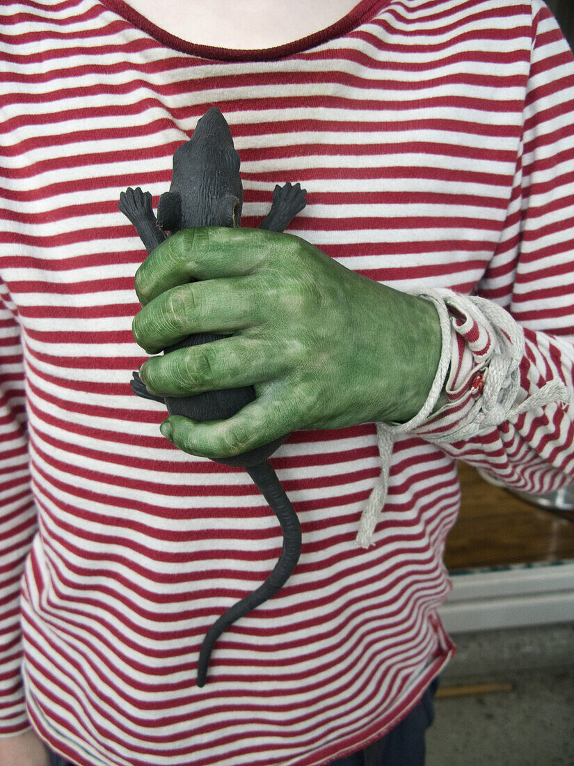 A person with a green hand holding a toy rat