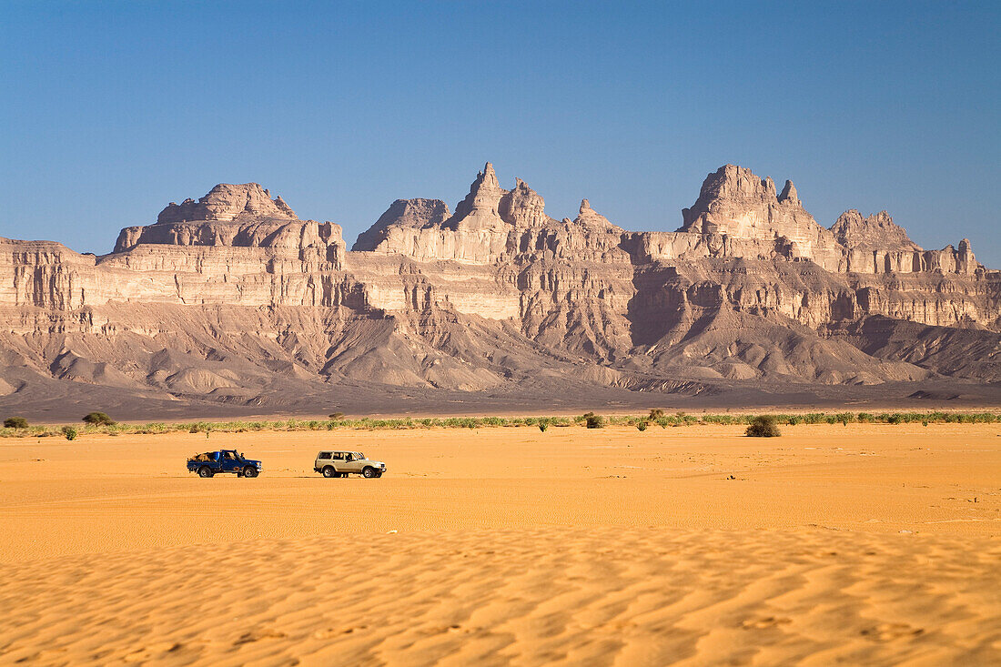 Sand and jeeps in front of the Idinen mountains in the libyan desert, Libya, Sahara, North Africa