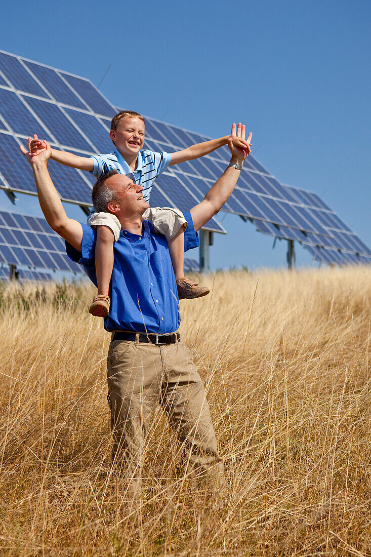 Solarpark bei Lieschensruh, Mann mit Sohn auf den Schultern erfreuen sich an der Sonne, Edertal, Hessen, Deutschland, Europa