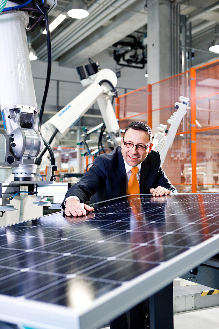 Geschäftsmann kontrolliert die Solarmodulproduktion in der Fertigung, Berlin, Deutschland, Europa