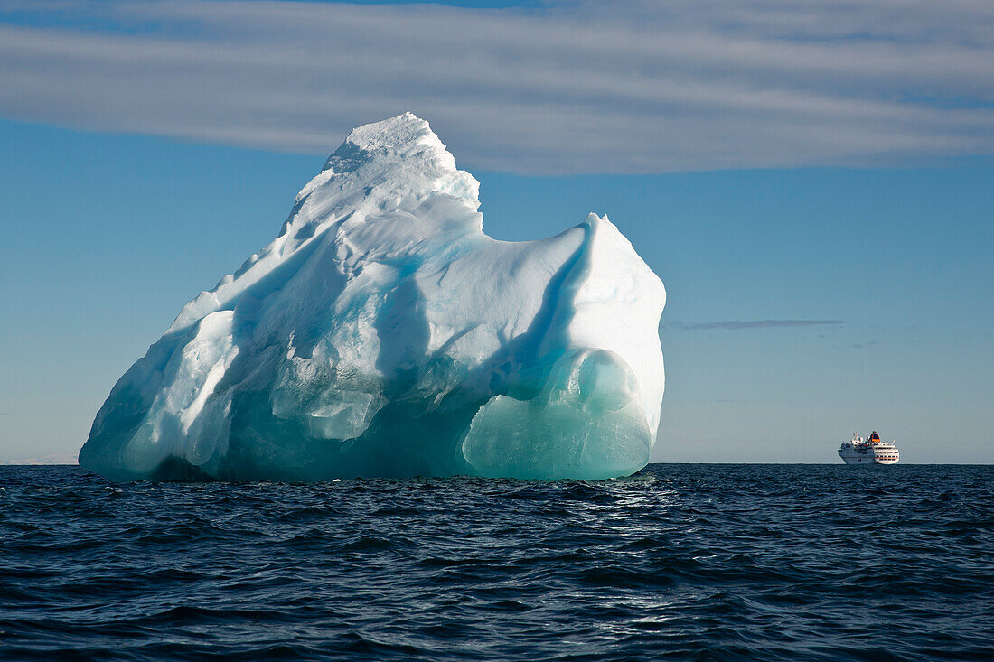 Eisberg im strahlenden Sonnenlicht mit Expeditions-Kreuzfahrtschiff MS Hanseatic (Hapag-Lloyd Kreuzfahrten) im Hintergrund, Bird Point, Ross Insel, Antarktis