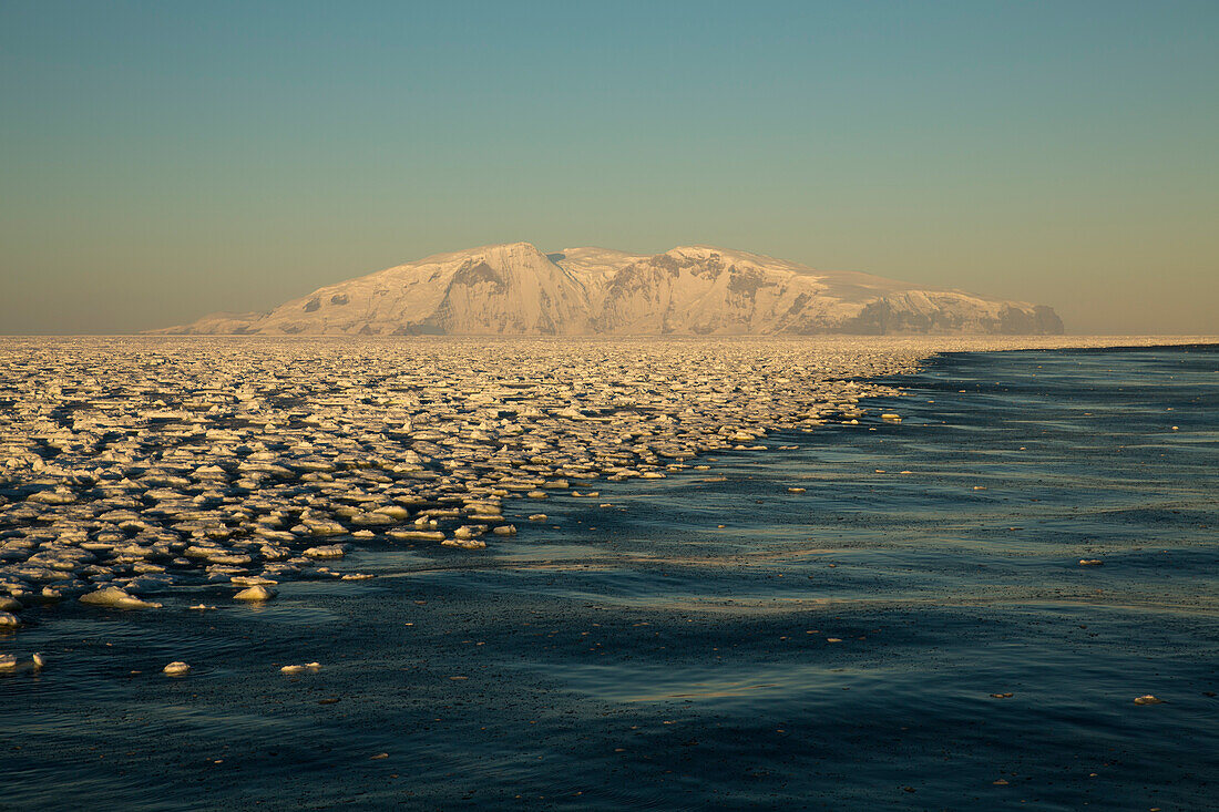 Eisschollen schwimmen im Meer und bilden eine Linie entlang der Küste, im Hintergrund verschneite Berge, Terra Nova Bay, Antarktis