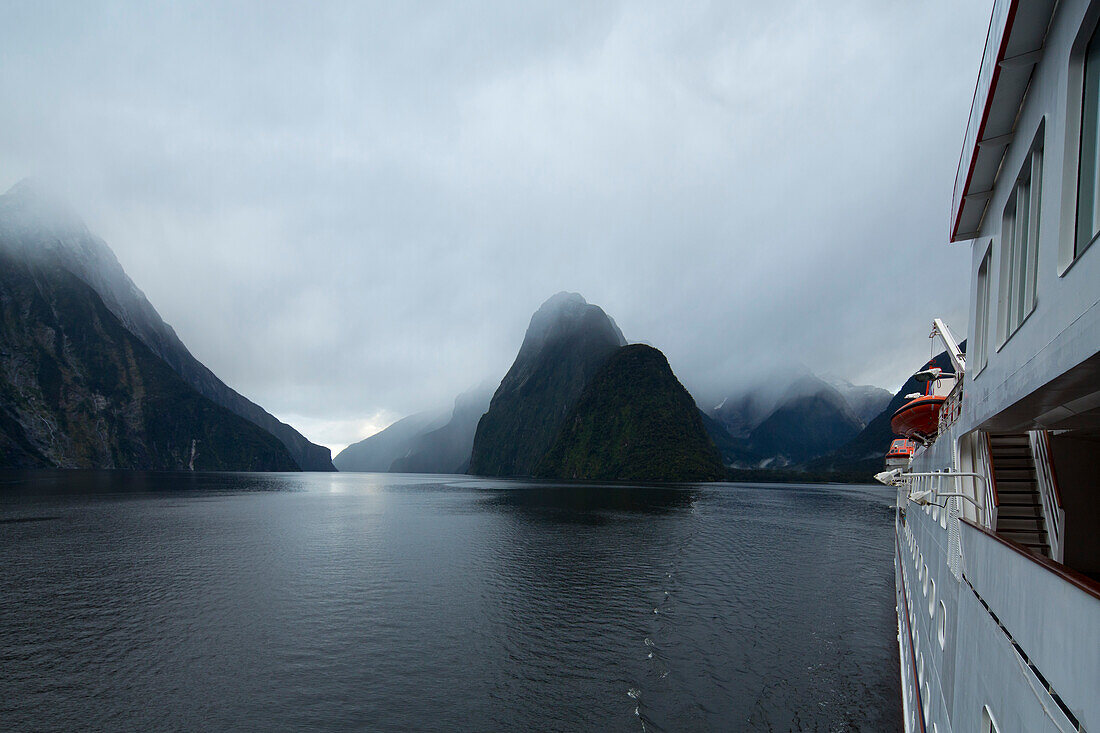 Side of expedition cruise ship MS Hanseatic (Hapag-Lloyd Cruises) in Milford Sound overcast with clouds, Milford Sound, Fiordland National Park, South Island, New Zealand