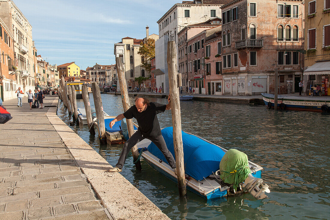 Fondamenta, boat moorings, motor boats, personal boats, canal, palina, paline, poles for mooring boats, man jumps from boat, Venice, Italy